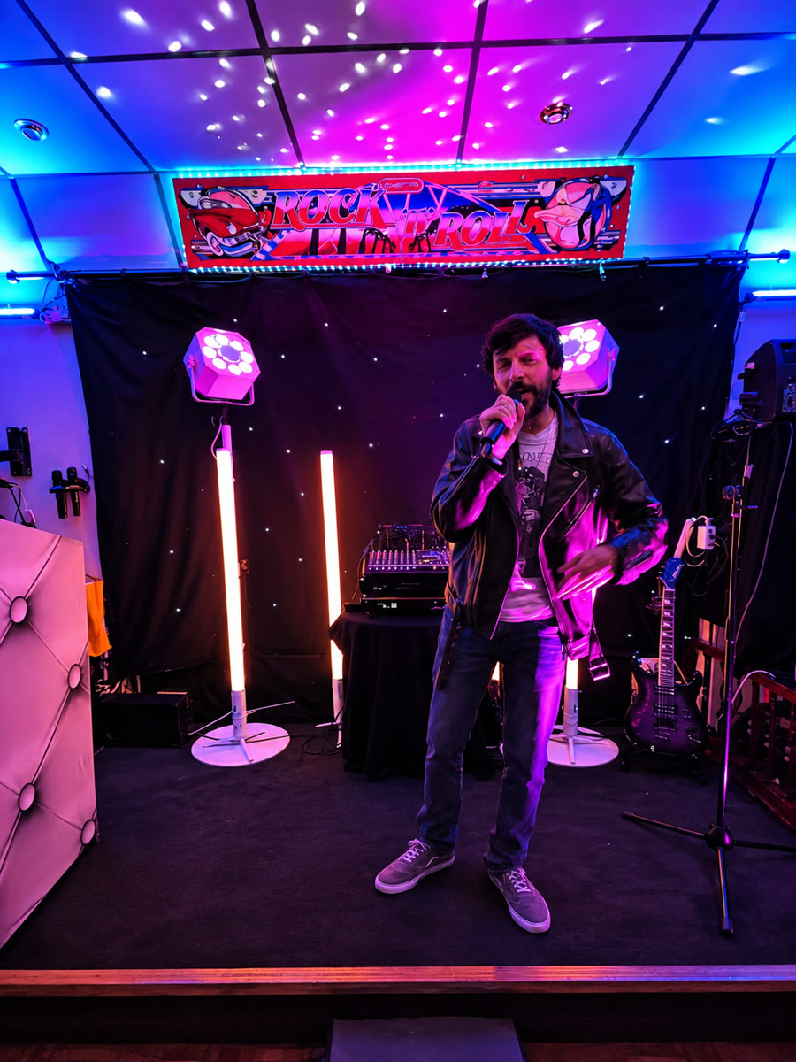 Man singing into a microphone on stage at a karaoke night