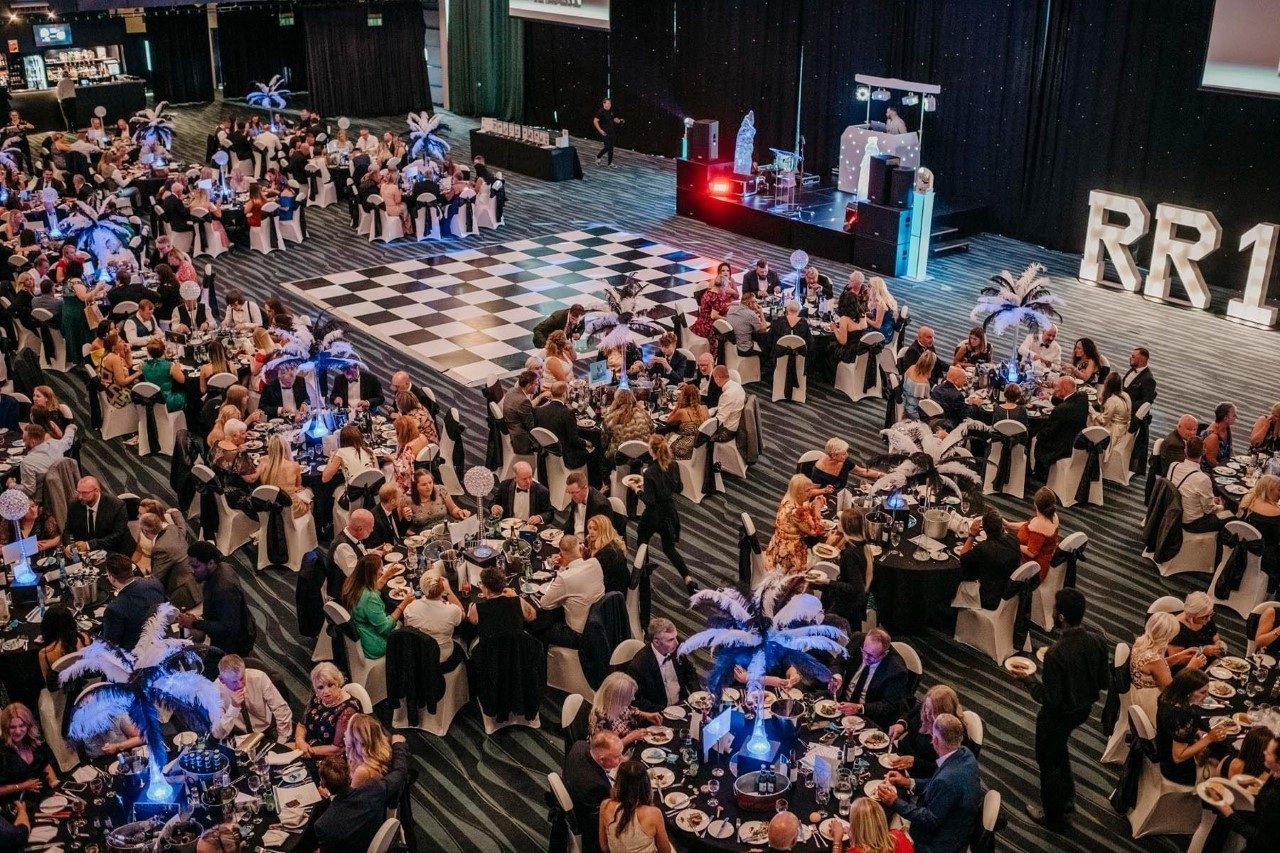 Aerial view of a packed awards dinner with a checkerboard dancefloor and DJ booth