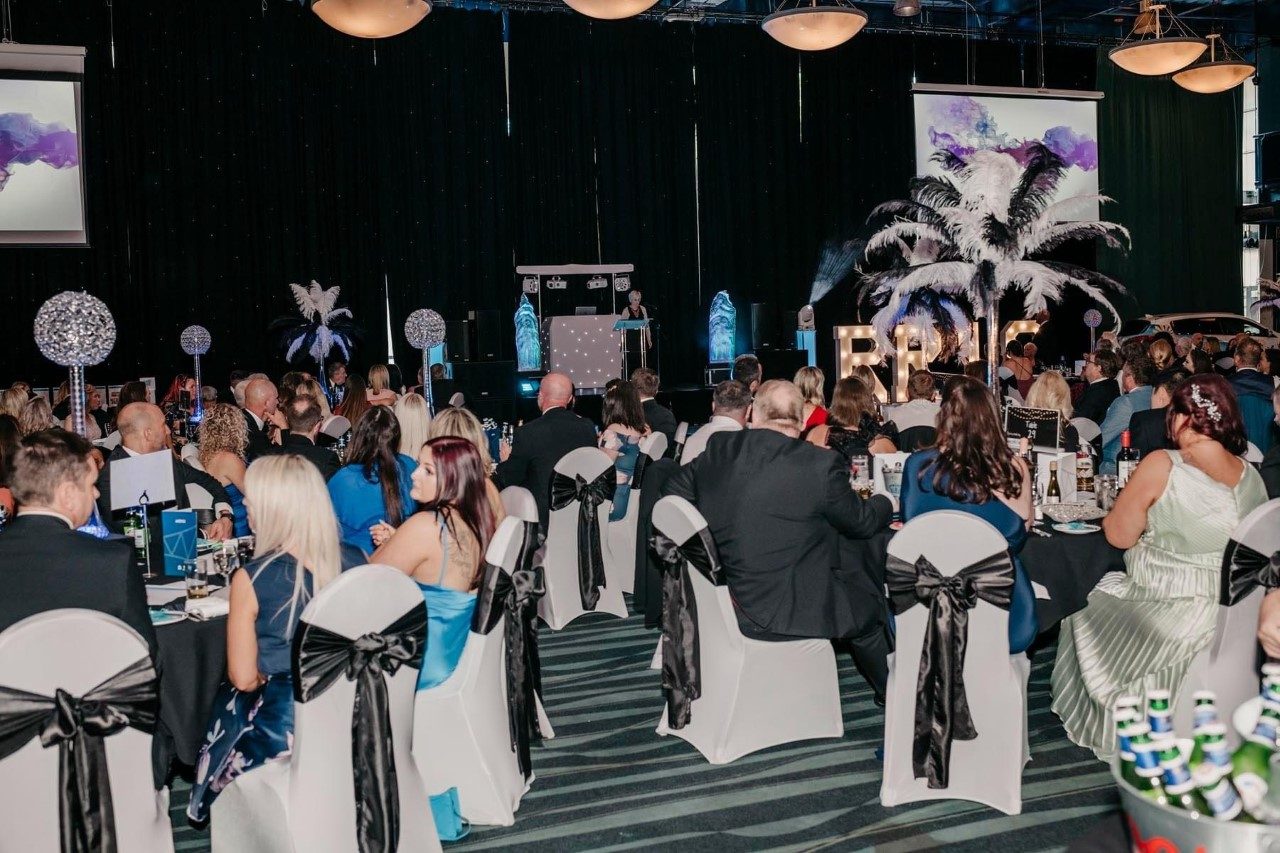 Guests gathered on the dancefloor facing the DJ booth at a black-tie event