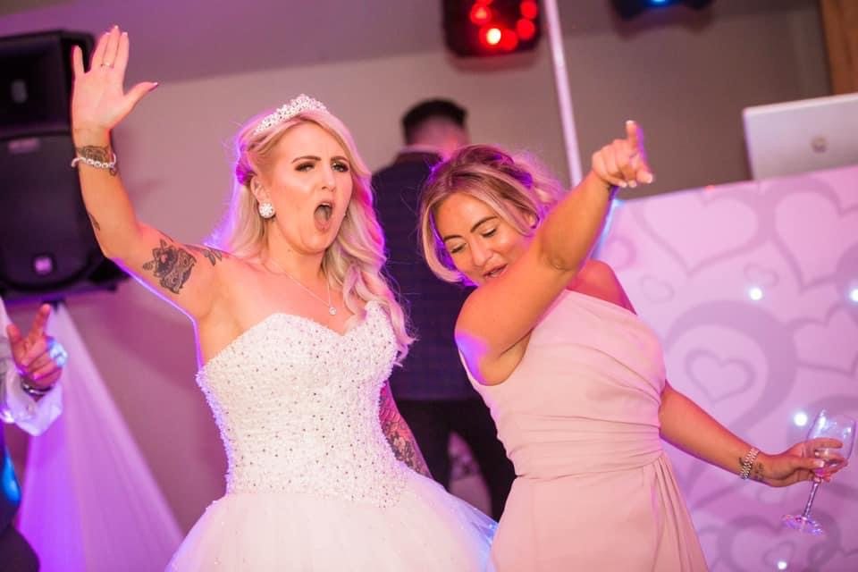 Bride dancing with a wedding guest in front of the DJ booth
