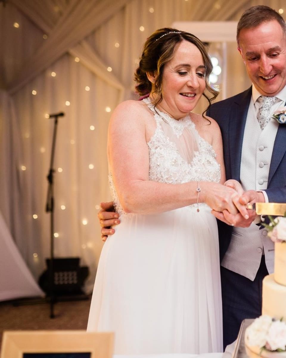Bride and groom cutting their wedding cake in front of the DJ booth